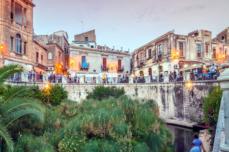 SYRACUSE, ITALY - AUGUST 16, 2014: tourists and locals visit the Arethusa Fountain in Ortigia, Syracuse, Italy. Ortigia is a small island Which is the historical center of the city of Syracuse, Sicily.のeditorial素材