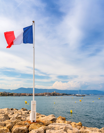 Antibes, France - June 29, 2016: view over the bay with France flag and alpes maritimes from Cap d'Antibes, Antibes. Antibes is a popular seaside town in the heart of the Cote d'Azurの写真素材