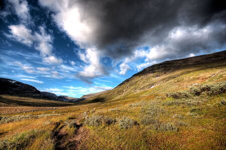 clouds come over the mountains of sweden letting the sun shine on the valley