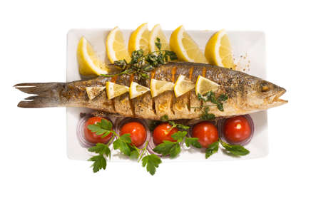 fish served with tomatoes and vegetables on big wooden board over tableの写真素材