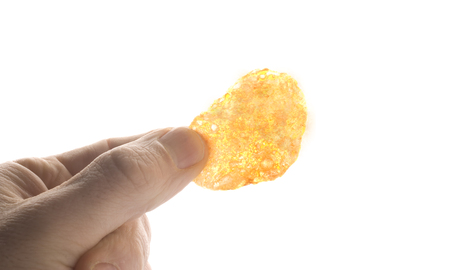 Fingers hold a potato chip - isolated on white backgroundの写真素材