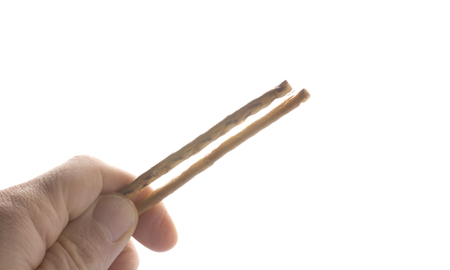 Fingers hold a salt rod, isolated on white backgroundの写真素材