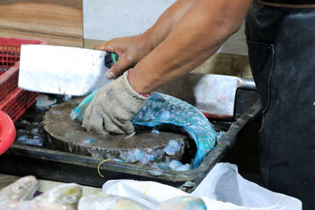 A man dismantles a fish at night market - Kota Kinabalu Borneo Sabah Malaysia Asia