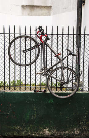 a bike hanging on a fence in a city