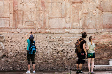 tourist look at details of roman frescoes in Pompeii, Italy