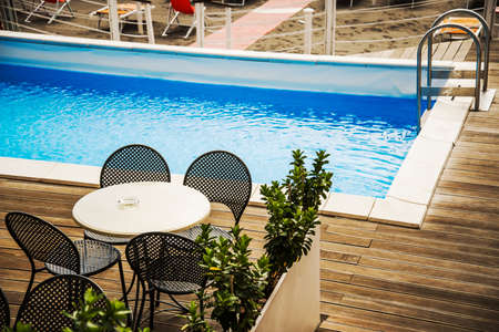 a pool with tables and chairs nearby a beachのeditorial素材