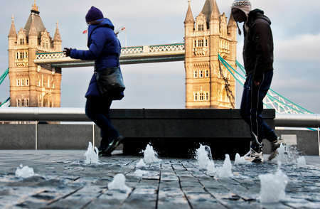 People near Thames river in modern area in London, UK