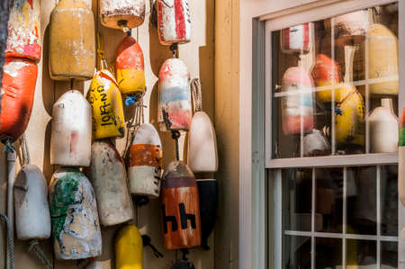 Old colorful lobster buoys against a weathered cedar shake wall.
