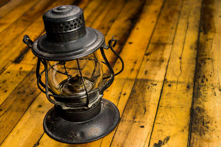 Old oil lantern isolated on wooden floorの写真素材