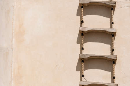 Ladder with rope hanged on a wallの写真素材