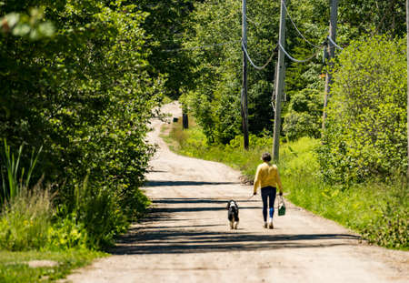 A woman walks with her dog in a park in Maine, USAの写真素材