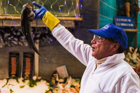 NAPLES, ITALY - DECEMBER 14: Fish seller show a fish in a market on December 14, 2014 in Naples,...