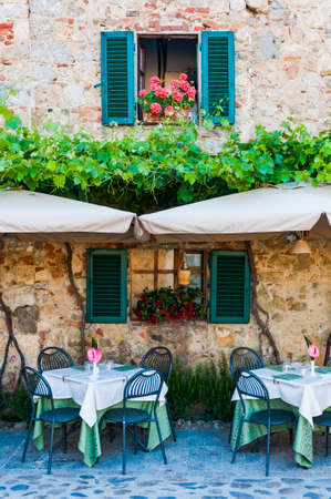 Tables of an Italian restaurant in the street of Monteriggioni, Italyの写真素材