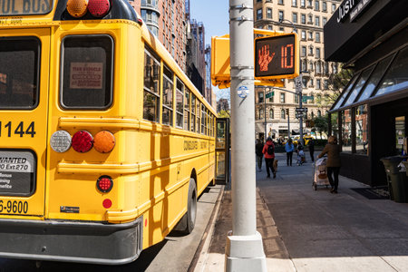School bus partking near a buildings at the side and few people in New York City on Spring Day