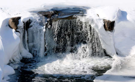 small waterfalls from a frozen lake in ontario, canada; picture taken in early marchの写真素材
