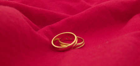 two wedding rings on a red cloth backgroundの写真素材