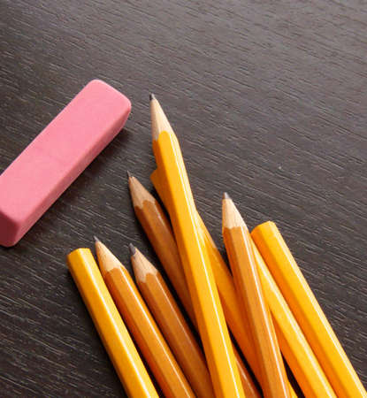 many pencils and a pink rubber on a black deskの写真素材