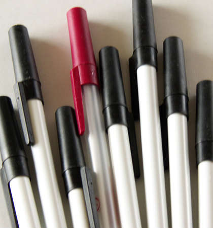 one red pen among many black onesの写真素材