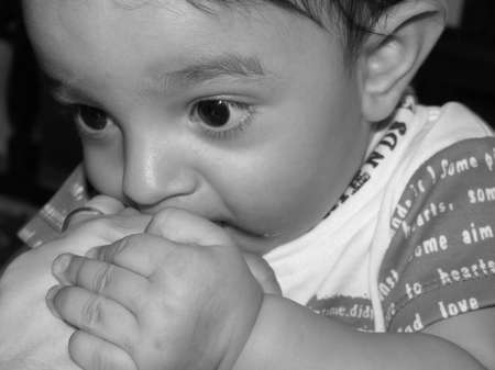 seven month old boy holding his mother's hand near his mouthの写真素材