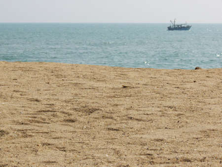 ocean beach with boat near the horizonの写真素材