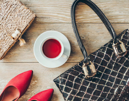 Women's accessories on a wooden background. Women's shoes, bag, cup of tea.の素材