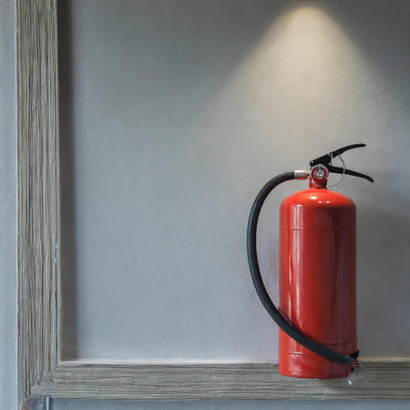 Fire extinguisher on wood shelf and wall background with copy space.の素材