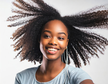 Young african american woman with afro hairstyle and headphones listening to music.の素材