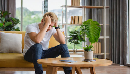 Stressed young man sitting on the floor in the living room.の素材
