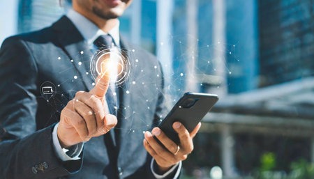 Businessman using mobile phone with light bulb icon on screen. Technology concept.の素材