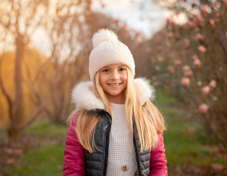 Portrait of a cute little girl in a pink jacket and white hat.の素材