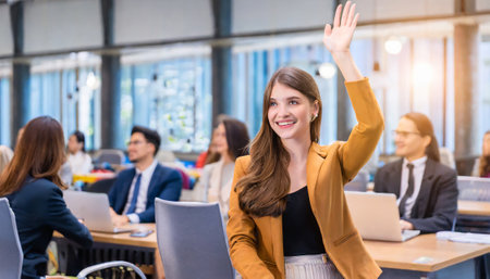 Businesswoman raising her hand in the office with colleagues in the backgroundの素材
