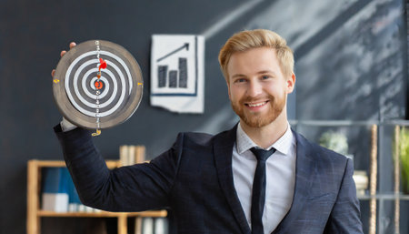 businessman holding target and looking at camera in office, focus on targetの素材