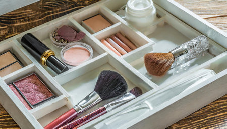 Makeup brushes and cosmetics in a wooden box on a wooden backgroundの素材