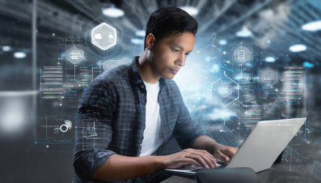 Young man using laptop in office against hud screen showing futuristic interfaceの素材