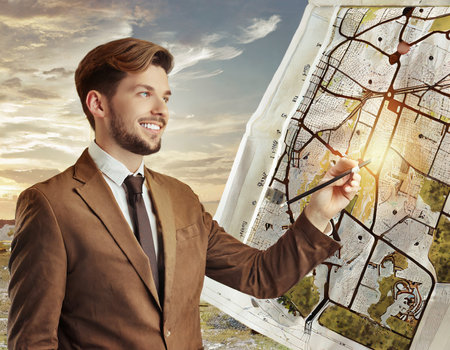 Handsome young man in suit drawing map of city. Travel conceptの素材