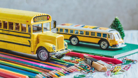 Back to school concept with yellow school bus and colorful pencils on wooden backgroundの素材