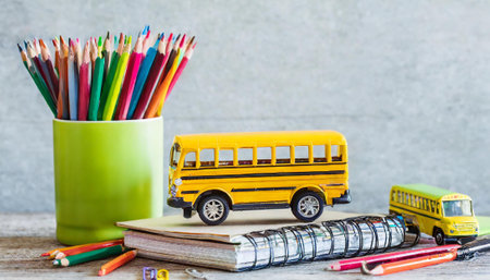 Back to school concept with school bus, pencils and notebook on wooden backgroundの素材