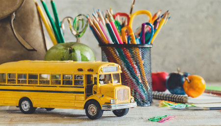 Back to school concept. School bus and school supplies on wooden backgroundの素材