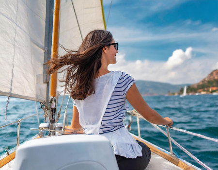 Beautiful young woman sailing on a yacht in a sunny summer dayの素材