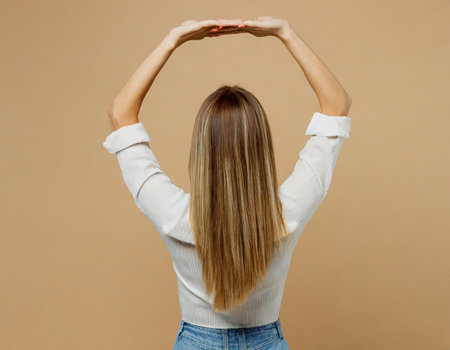 Back view of a young woman with long hair on a beige backgroundの素材
