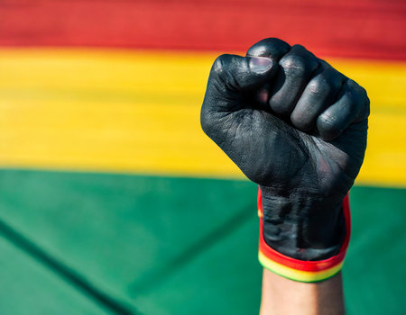 Close-up of a hand with a clenched fist on the background of the flag of Boliviaの素材
