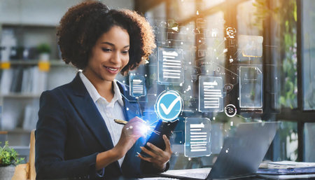 Successful businesswoman working with mobile phone and laptop computer in modern officeの素材