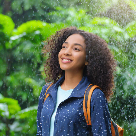 Portrait of a young african american woman with curly hair in the rainの素材
