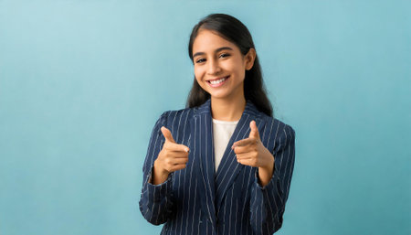 Portrait of a happy businesswoman showing thumbs up on blue backgroundの素材