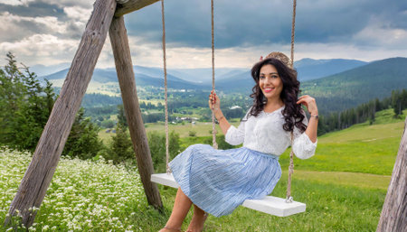 Beautiful young woman sitting on a swing in the Carpathian mountainsの素材