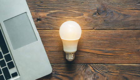 laptop computer and light bulb on wooden table, vintage color toneの素材