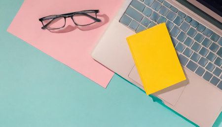 Notebook, glasses and laptop on a blue background. Top viewの素材