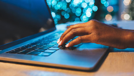Close-up of female hands typing on laptop keyboard at table in cafeの素材