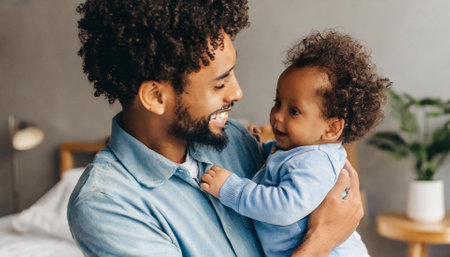 smiling african american father holding adorable little daughter in bedroomの素材
