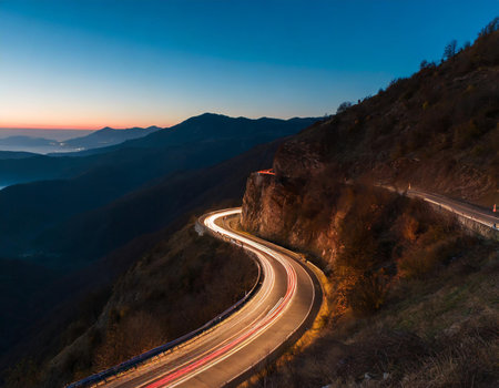 Mountain road in the mountains at sunset. Car light trails.の素材